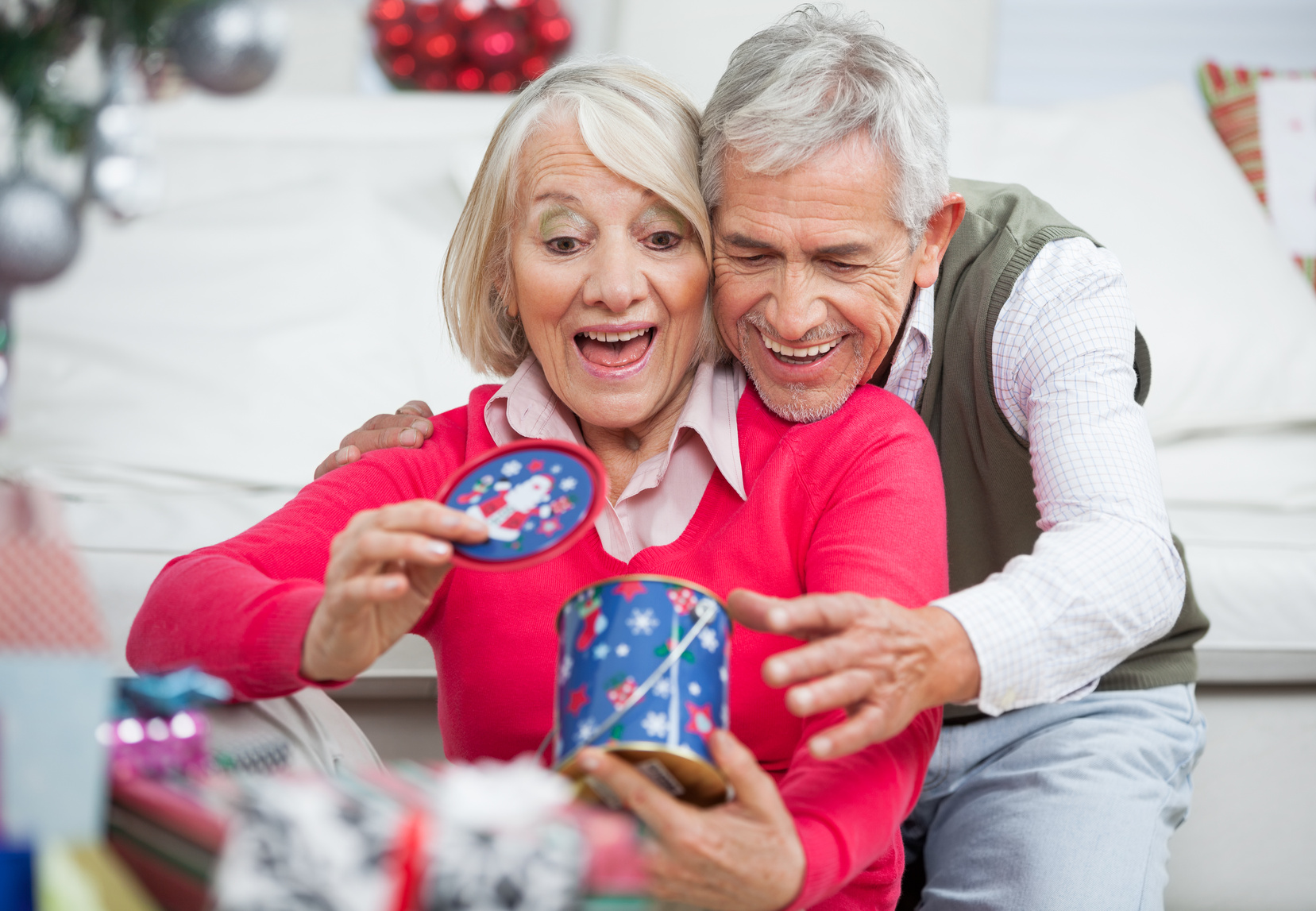 Surprised Senior Woman With Man Looking At Christmas Gift