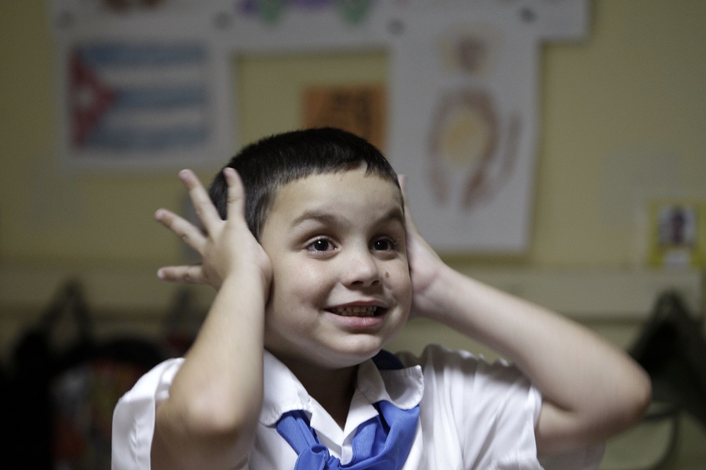 In this May 16, 2013 photo, Cristian Vazquez covers his ears during class at the Dora Alonso school in Havana, Cuba. Six-year-old Vazquez was diagnosed with autism in 2008 and began attending this special school that caters to the education of children with autism. Although Vazquez's education is paid for by the state, his parents say that it is difficult to acquire special materials for their son, like books that have figures, colors and pictograms. (AP Photo/Franklin Reyes)