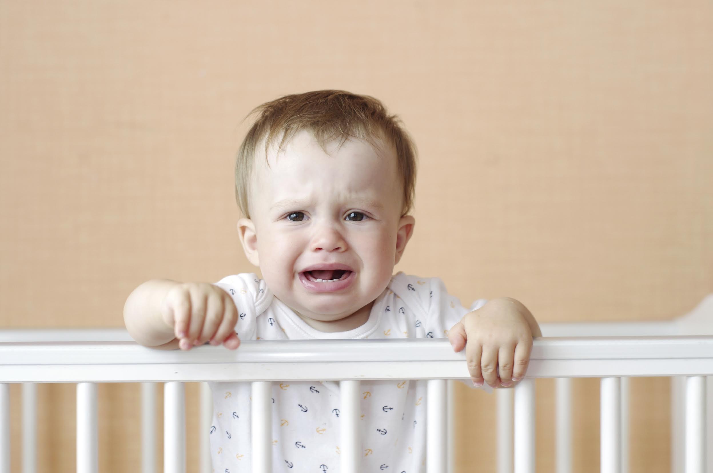 crying baby age of 11 months in white bed