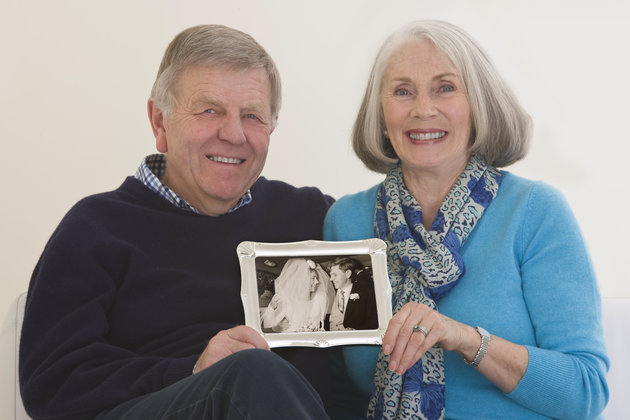 senior couple holding a framed wedding photogh