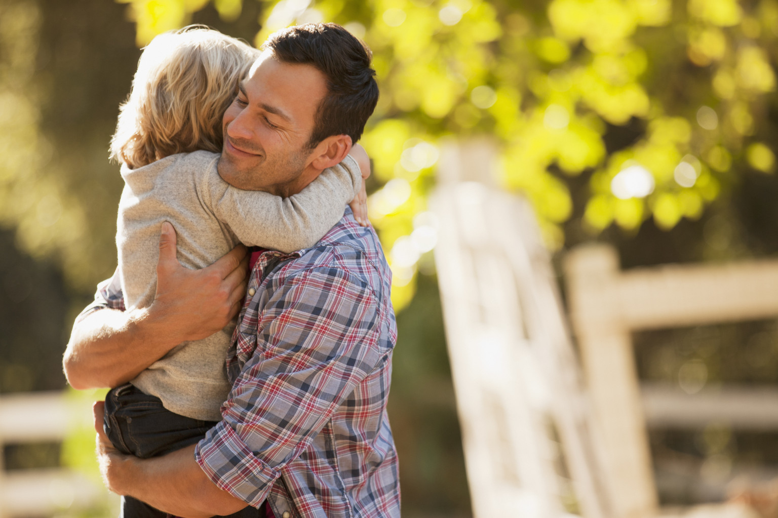 Smiling father hugging son outdoors.